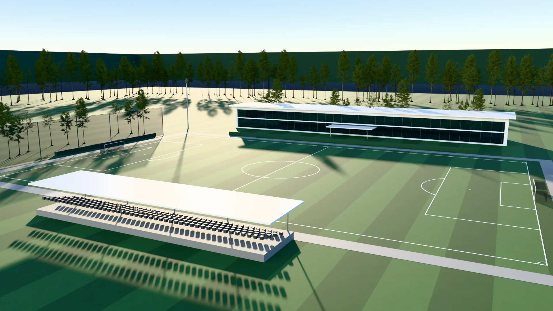An academy pitch on a summer day, with a covered stand in front and the clubhouse behind.